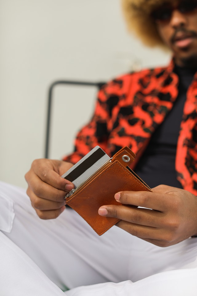 A person holding an orange wallet and a black card.