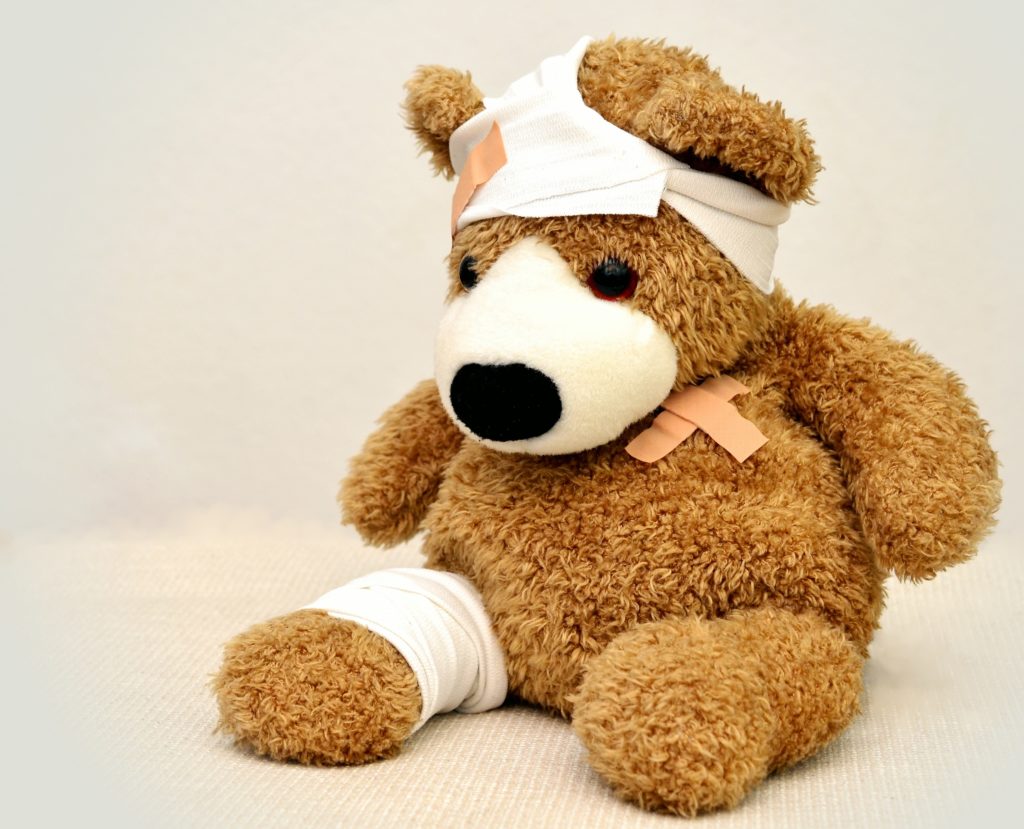 A teddy bear with bandages on its head and arm.