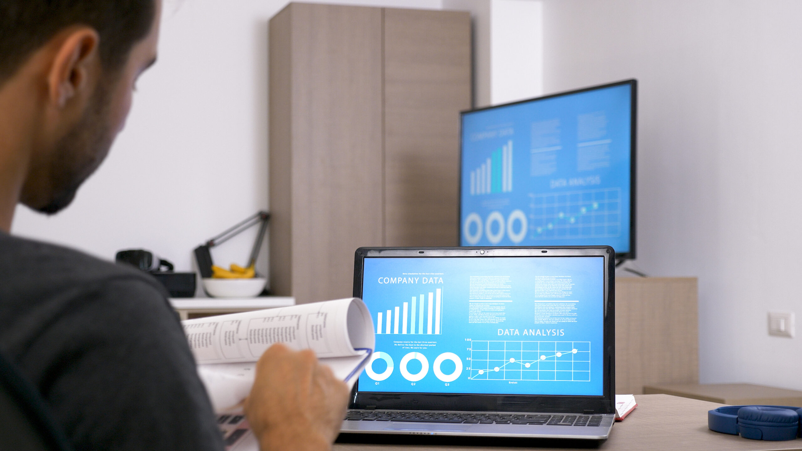 A person is looking at graphs on two computers.