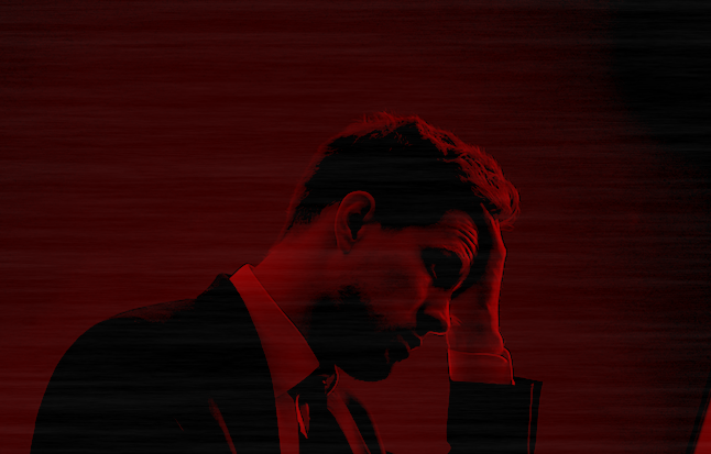 A man in a suit and tie holding his head.