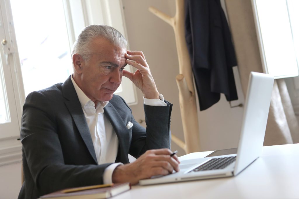 A man in suit and tie looking at his laptop.