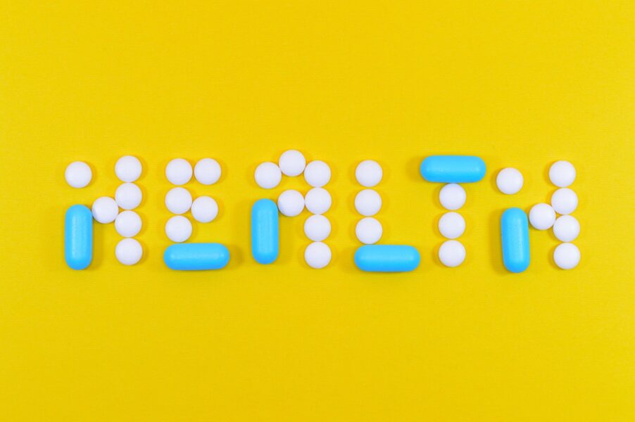 A yellow background with pills and tablets spelling out health.