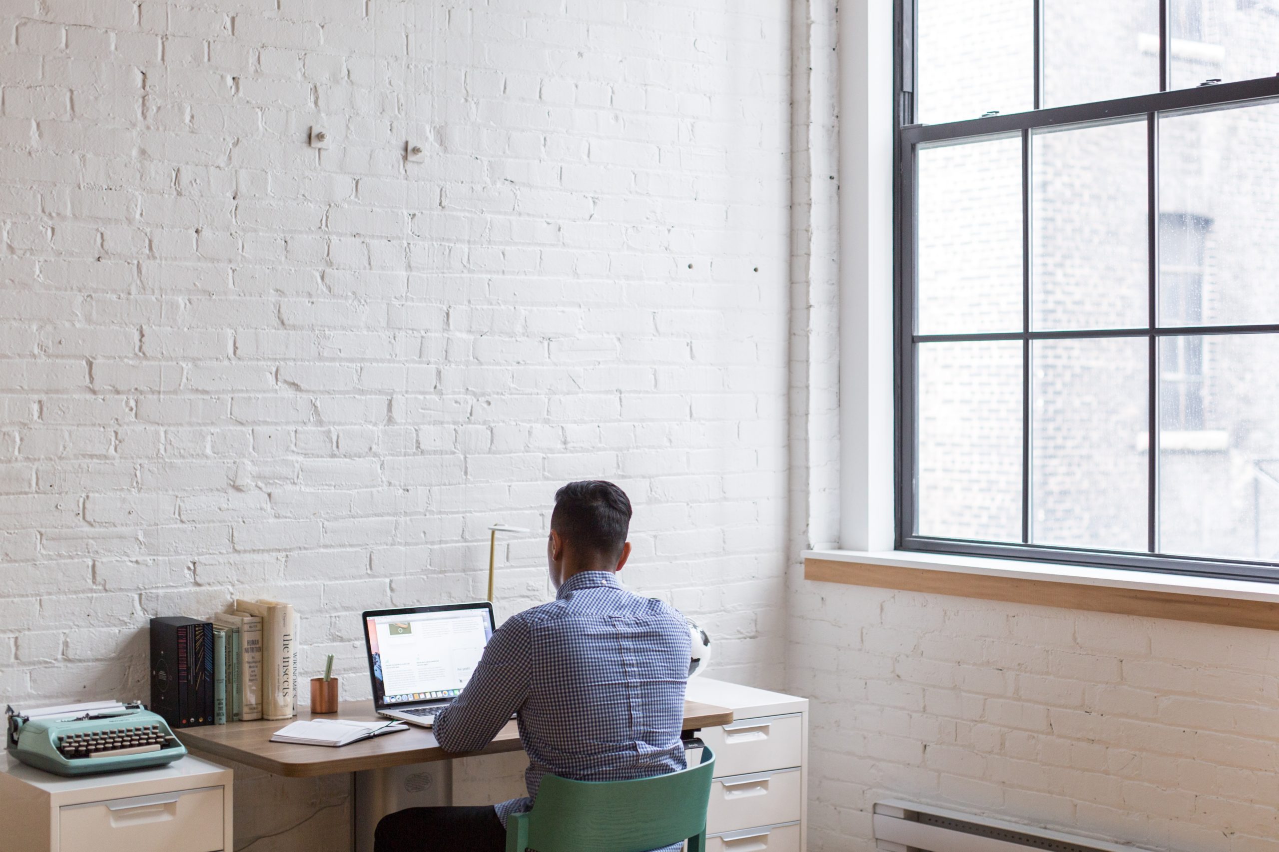 A man sitting at his desk working on a laptop.