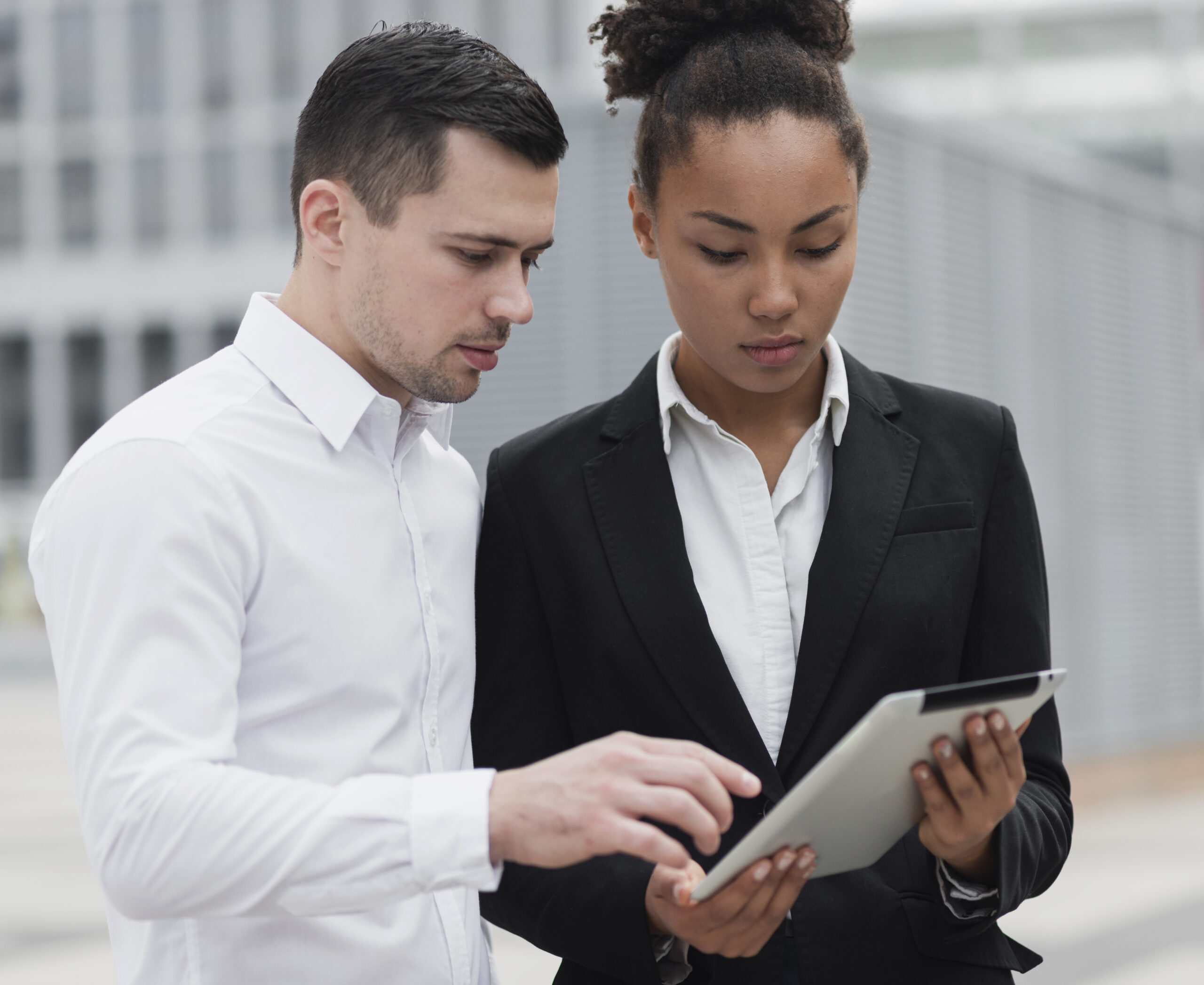 Two people looking at a tablet in front of each other.