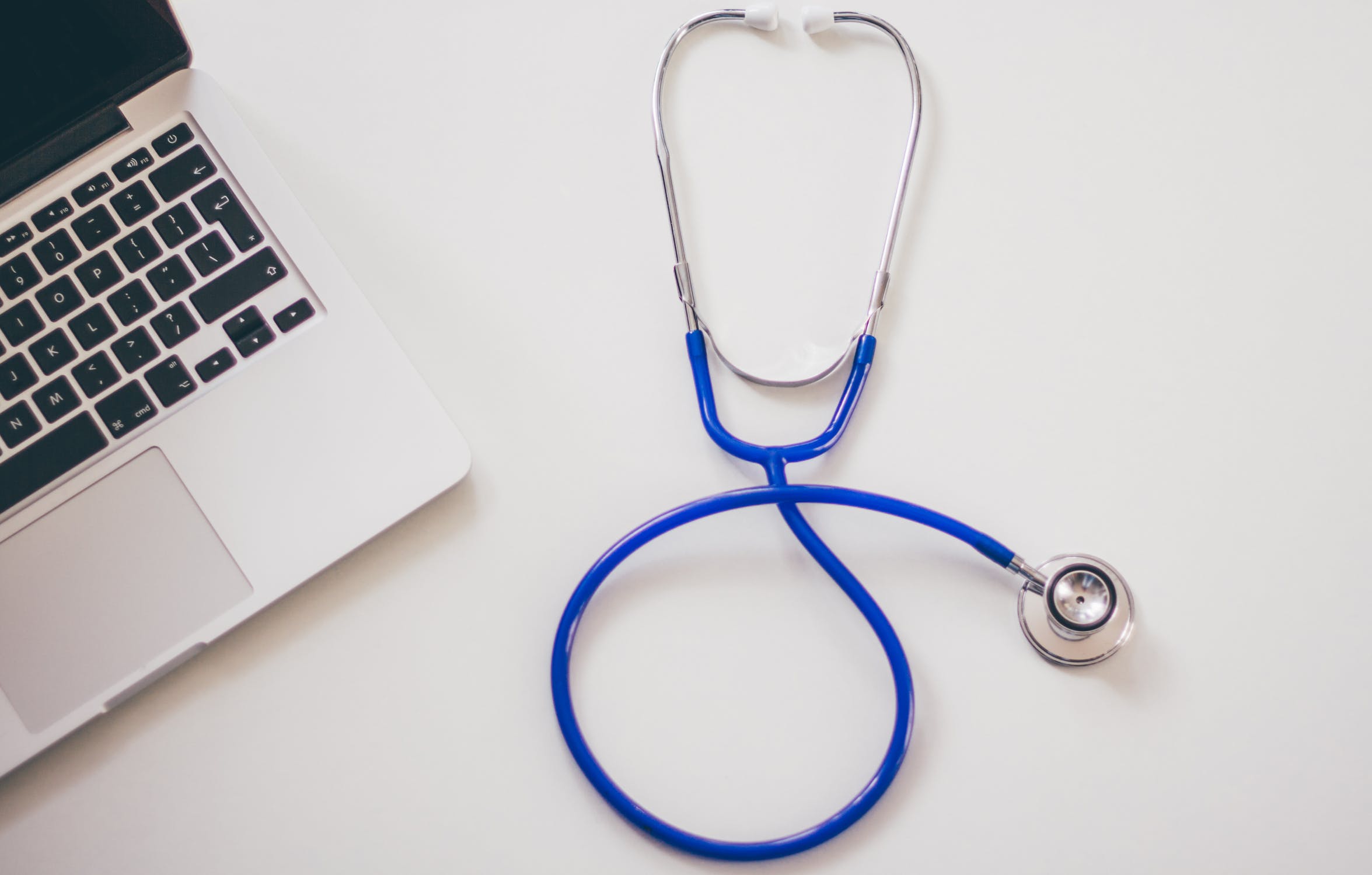 A stethoscope is laying on top of a laptop.